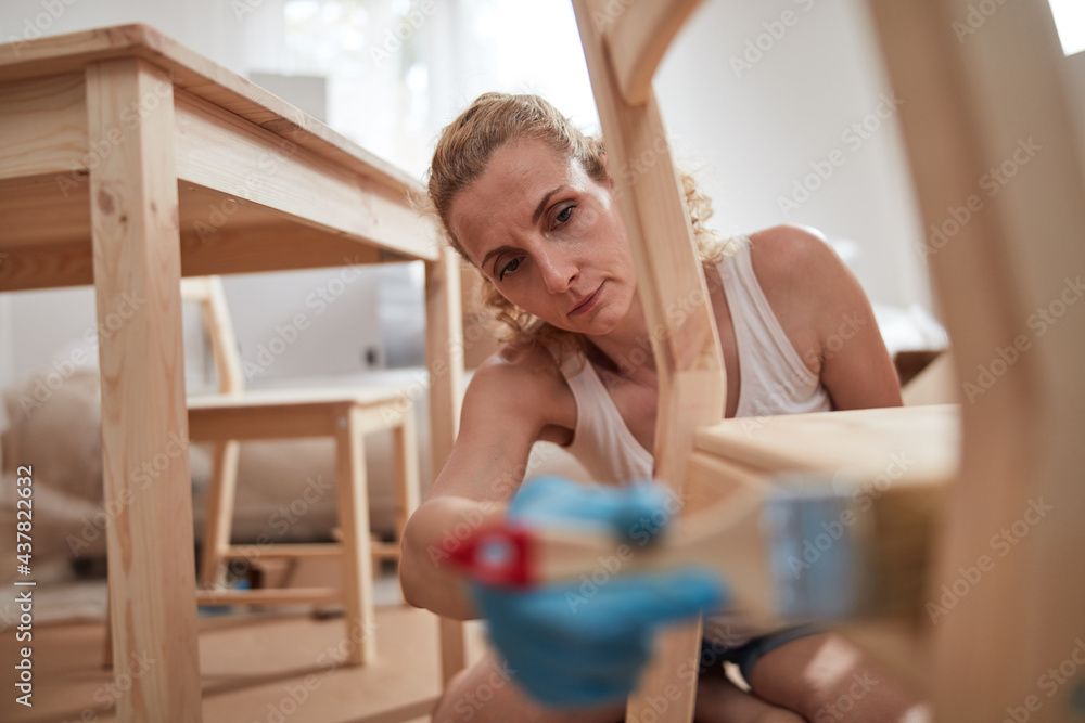 Woman painting and assembling furniture in new apartment, moving in and being hardworking. Woman painting and assembling furniture in new apartment, moving in and being hardworking.