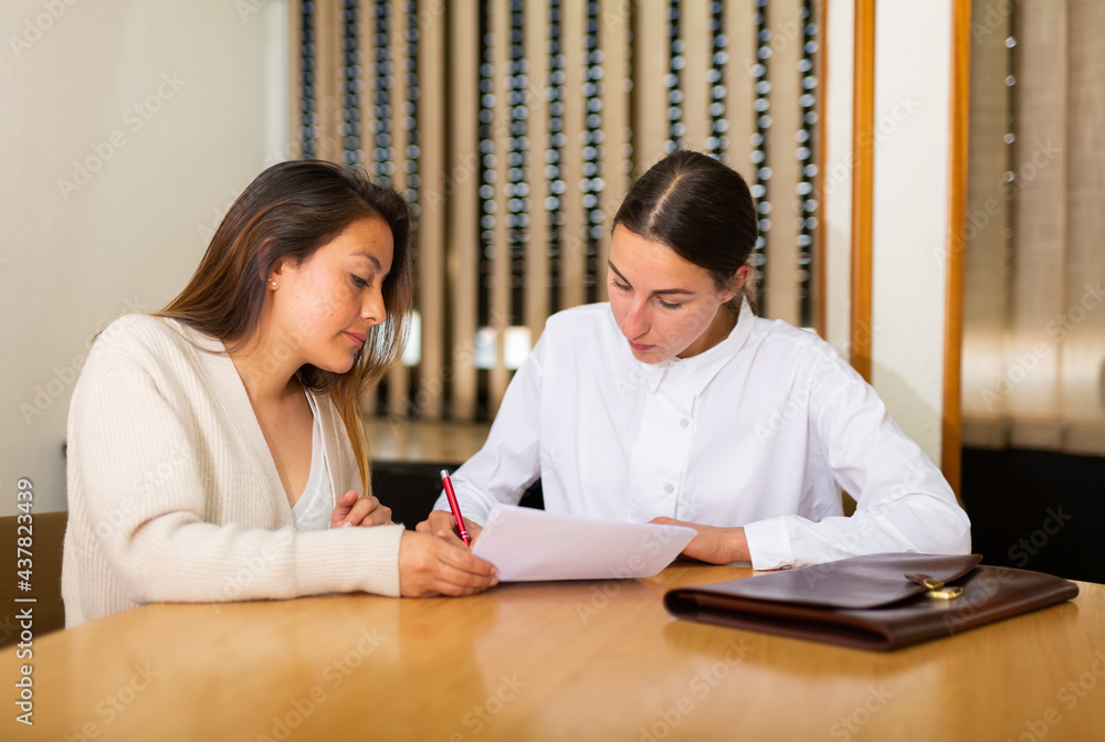 Obraz premium Two business woman in office interior filling up documents
