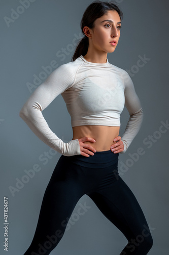 Young woman doing stretching lunge on grey background