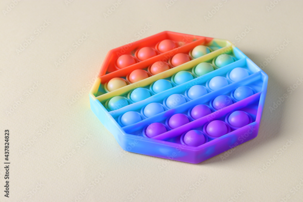 New popular silicone bright antistress pop it toy for child on light background. Simple dimple. Copy space New popular silicone bright antistress pop it toy for child on light background. Simple dimple. Copy space