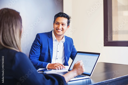 Handsome Indian man giving KYC interview to a woman with laptop in a bank or office