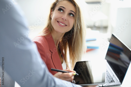 Smiling businesswoman holding stylus male colleague holds out her tablet