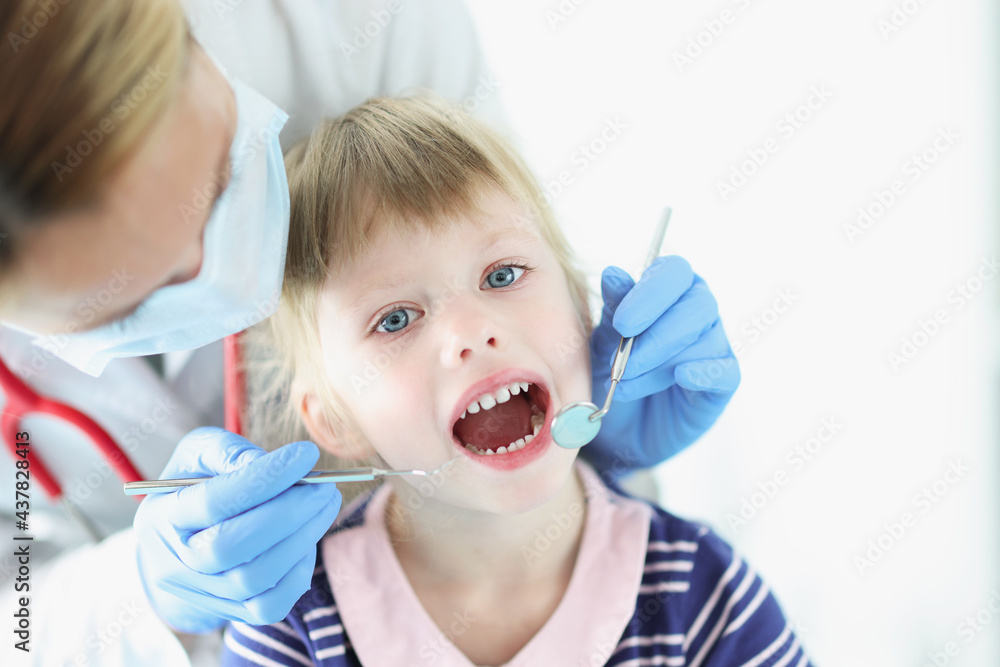 Dentist conducts medical examination of teeth of little girl Dentist conducts medical examination of teeth of little girl