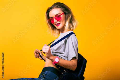 Fashion image of young happy woman wearing casual sportive outfit, backpack and neon glasses, healthy lifestyle concept.