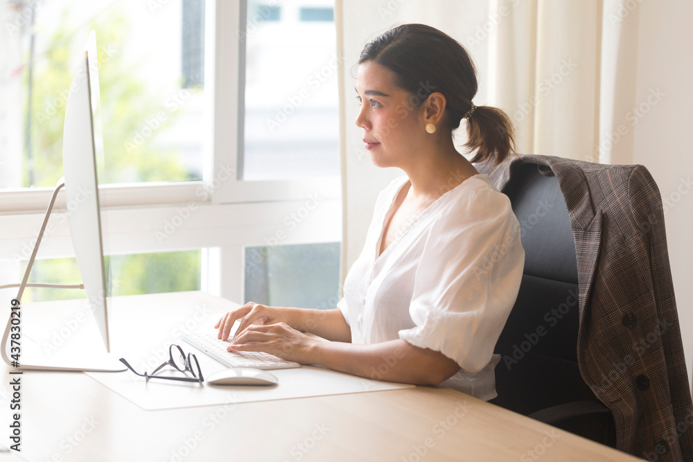 Beautiful Asian woman work from home, working on computer in living room at home. Social distancing lifestyle.