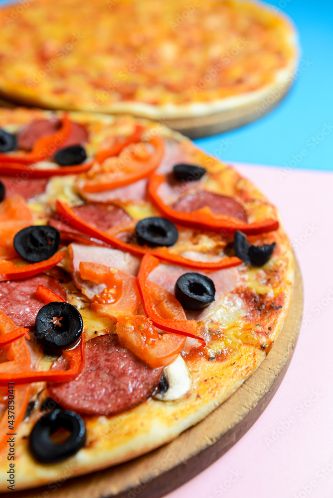 Two different kinds of pizza over pastel blue and pink background. Two different kinds of pizza over pastel blue and pink background.
