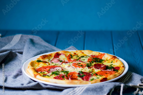 Cooked pizza on aged blue wooden surface background with copy space, side view.