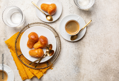 Italian breakfast. Rum baba and coffee espresso, glasses of water.  Light stone background, top view, copy space. photo