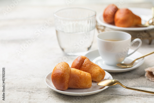 Italian breakfast. Rum baba and coffee espresso, glass of water. Selective focus. Light background. photo