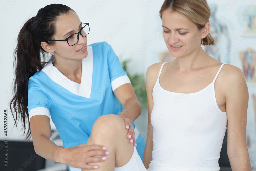 Female doctor conducts a physical examination of knee joint of patient Female doctor conducts a physical examination of knee joint of patient