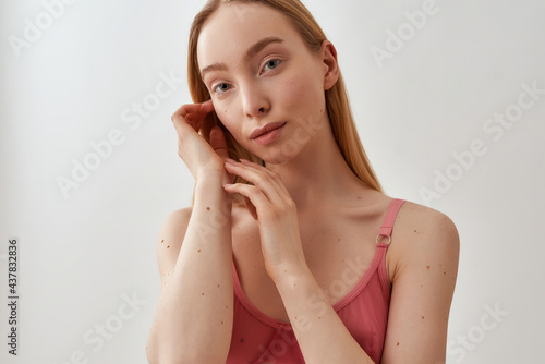 Portrait of young caucasian blonde female model wearing pink transparent bra looking at camera, posing isolated over light gray background photo