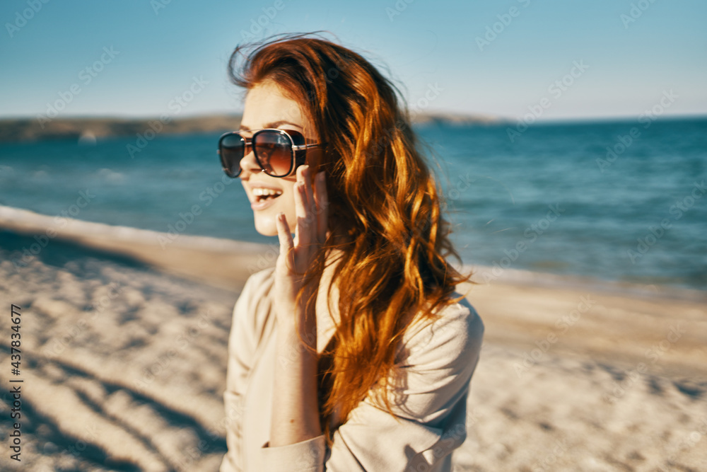 side view of red-haired woman model in shirt and glasses near the sea on the beach side view of red-haired woman model in shirt and glasses near the sea on the beach