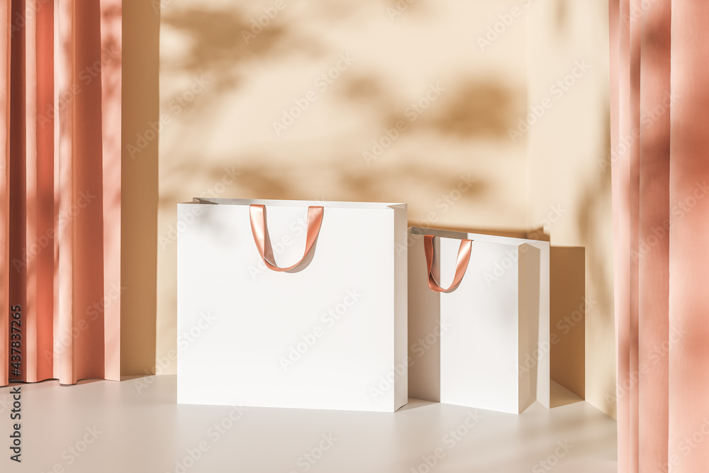 Two white paper bags with pink handles on a beige background with ...