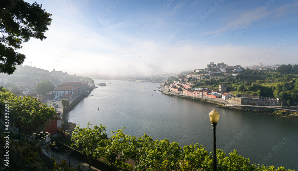 Summer morning view above beautiful Porto city from Portugal. Foggy cityscape in the start of a sunny day. Landmarks from Europe. A place to travel.