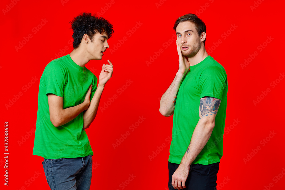 two men in green t-shirts stand next to communication Friendship red background two men in green t-shirts stand next to communication Friendship red background