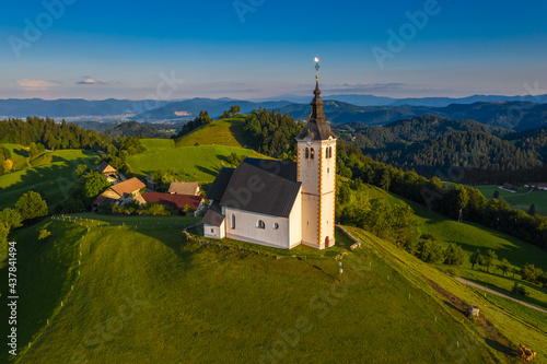 Sveti Andrej, Slovenia - Aerial drone view of Saint Andrew church (Sv. Andrej) at sunset in Skofja Loka area. Summer time in the Slovenian alps with clear blue sky