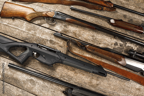 Many hunting rifles on weathered wooden surface