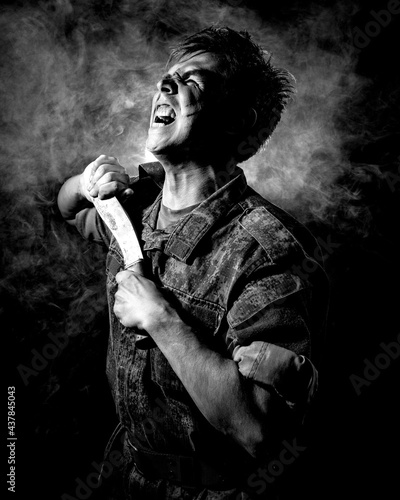 Black white portrait of a soldier in combat coloring, scarred and bruised, holding a machete and screaming on a black background with smoke