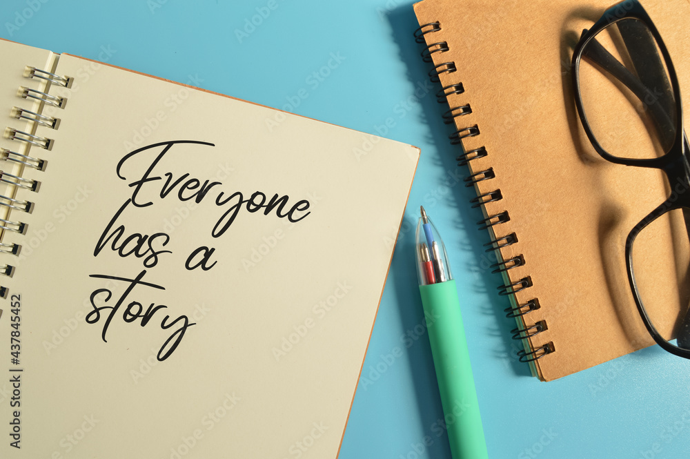 Top view of pen and notebooks written with EVERYONE HAS A STORY Top view of pen and notebooks written with EVERYONE HAS A STORY