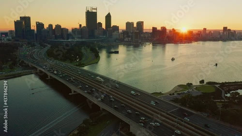 Aerial footage of the sun rising behind the Perth skyline and Swan River on a clear misty morning in Western Australia.