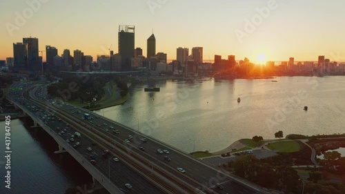 Aerial video of the sun rising above the Perth City skyline and Swan River on a hazy morning in Western Australia.