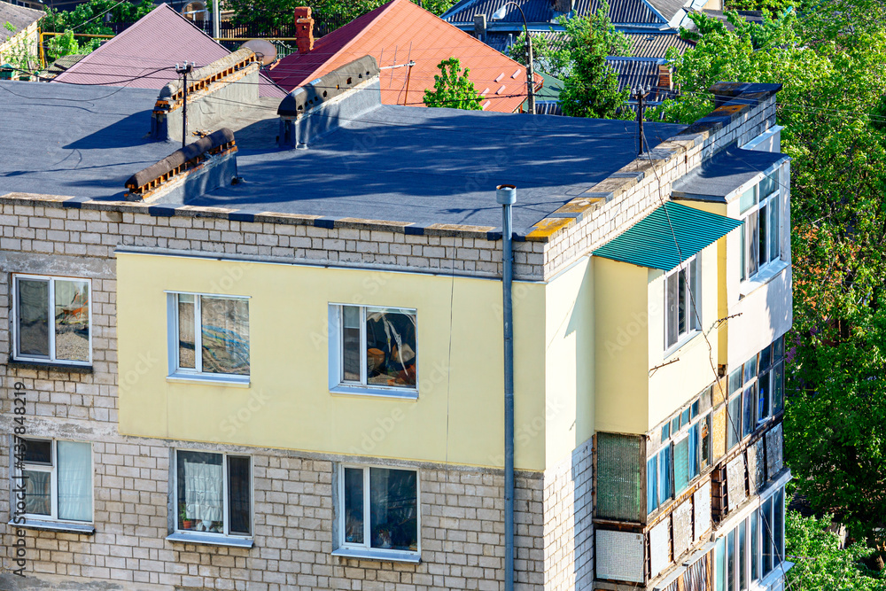 Thermal insulation of an apartment with polystyrene foam , exterior view . Bituminous roof with chimney