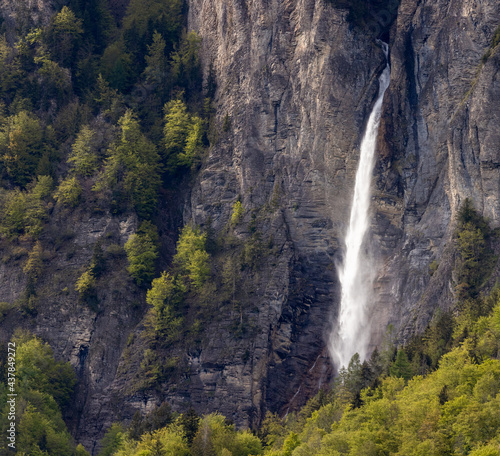 Waterfall Muelibachfall over steep cliff with summer forest in switzerland brienz