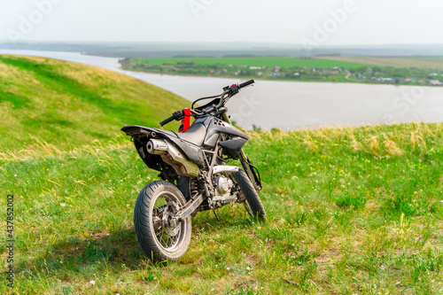 The motorcycle stands on a hill overlooking a beautiful landscape with green meadows. Togliatti, Russia - 20 May 2021: