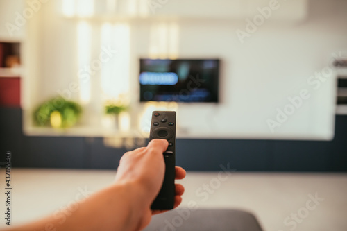 Selective focus image with a remote control and relaxing feet and tv in a modern living room. 