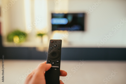 Selective focus image with a remote control and relaxing feet and tv in a modern living room. 