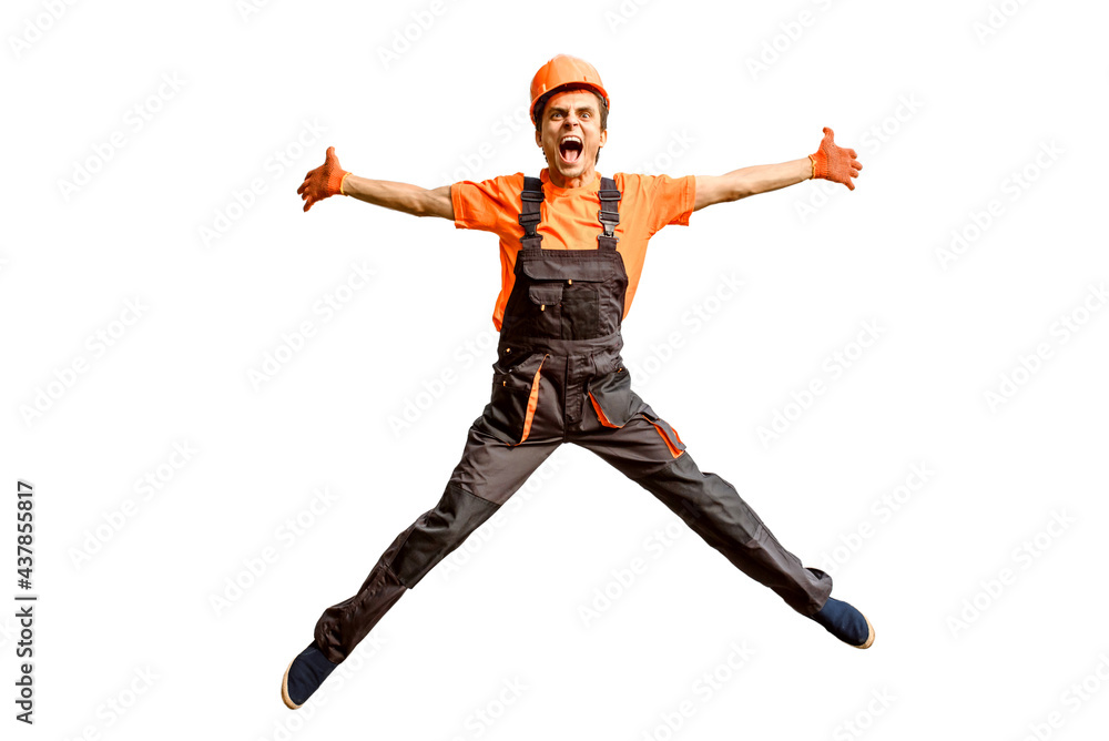 Young happy laughing caucasian man builder construction worker in a safety helmet is jumping in front of the roller door lifting gates