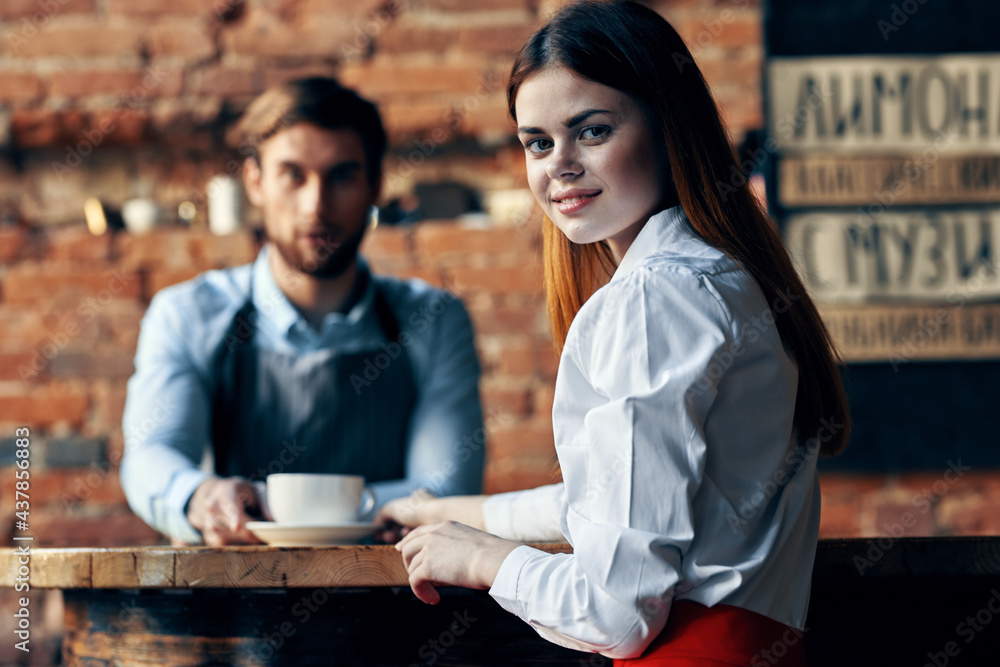 happy woman with cup of coffee and man bartender in apron
