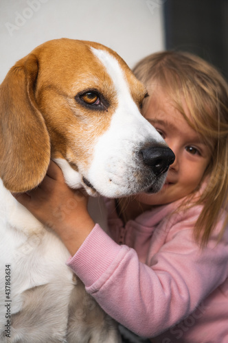 2 year old child hugging best friend dog. Happy childhood with pet Beagle. Dog background