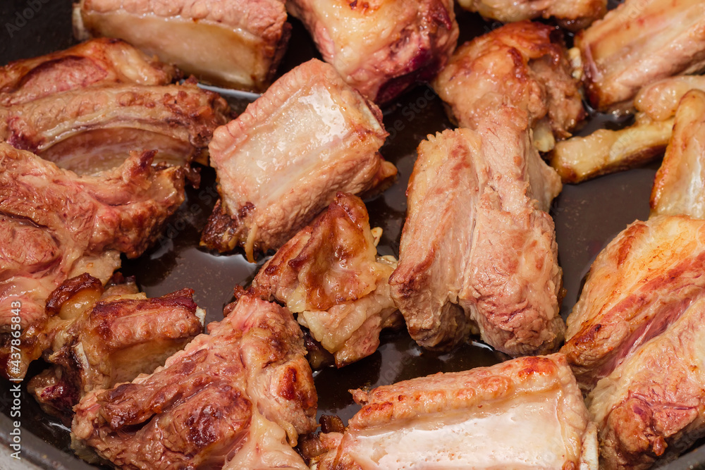 Fried pork ribs in frying pan close-up