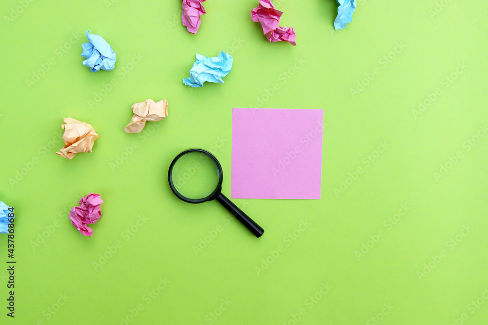 Top view photo of a magnifying glass and blank sticker on a green background. Top view photo of a magnifying glass and blank sticker on a green background.