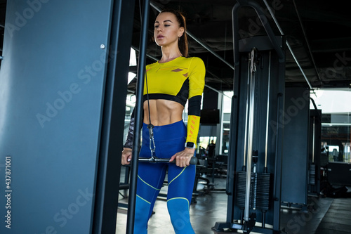 Sporty girl performing cable straight arm pulldown in crossover at gym