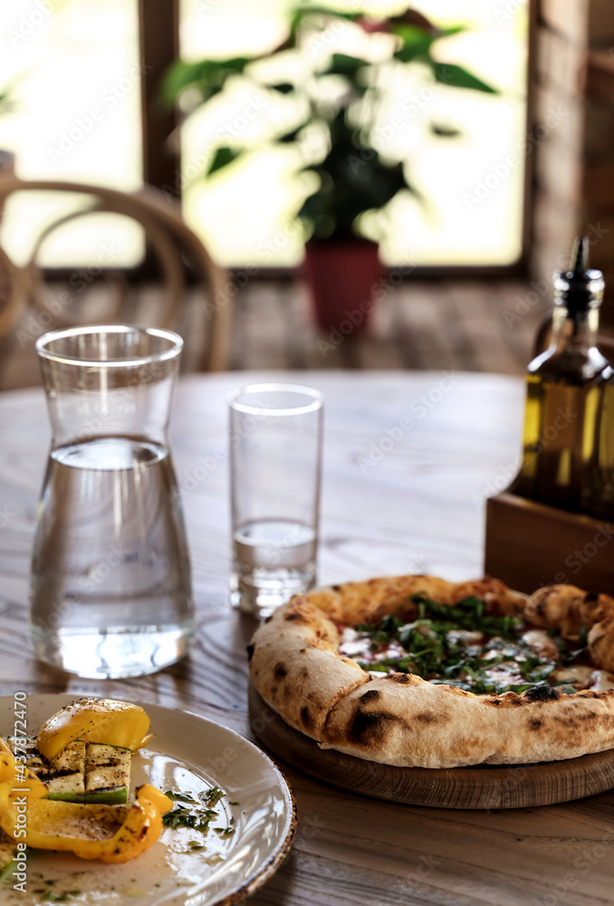 Pizza and grilled vegetables on wooden table in vintage style. Italian restaurant background for your design.
