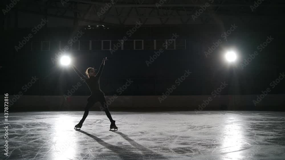 Skaters training on the indoor ice arena in the dark with spotlights