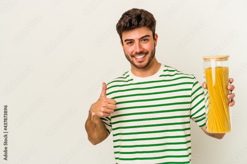 Young caucasian woman holding pasta jar isolated on white background smiling and raising thumb up Young caucasian woman holding pasta jar isolated on white background smiling and raising thumb up