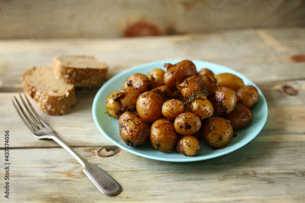 Whole fried potatoes. A plate of peeled baked potatoes. Appetizing baby potatoes with a golden crust.