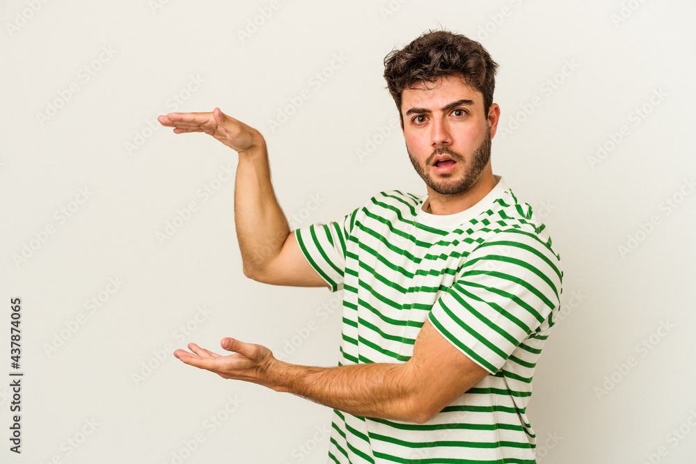 Young caucasian man isolated on white background shocked and amazed holding a copy space between hands. Young caucasian man isolated on white background shocked and amazed holding a copy space between hands.