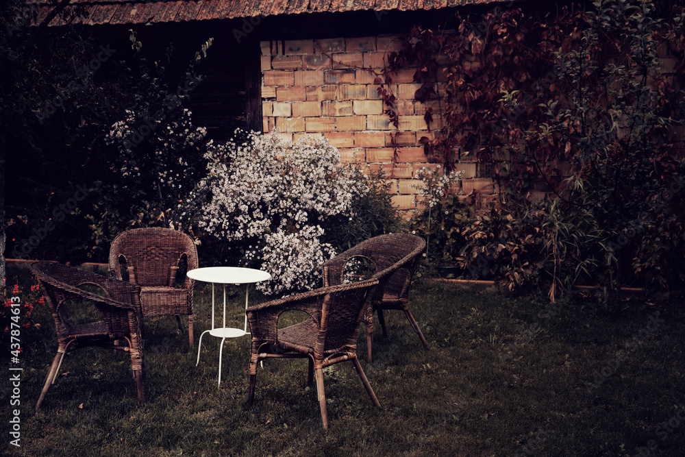 Vintage styled image of an old garden in autumn with chairs and a table. 