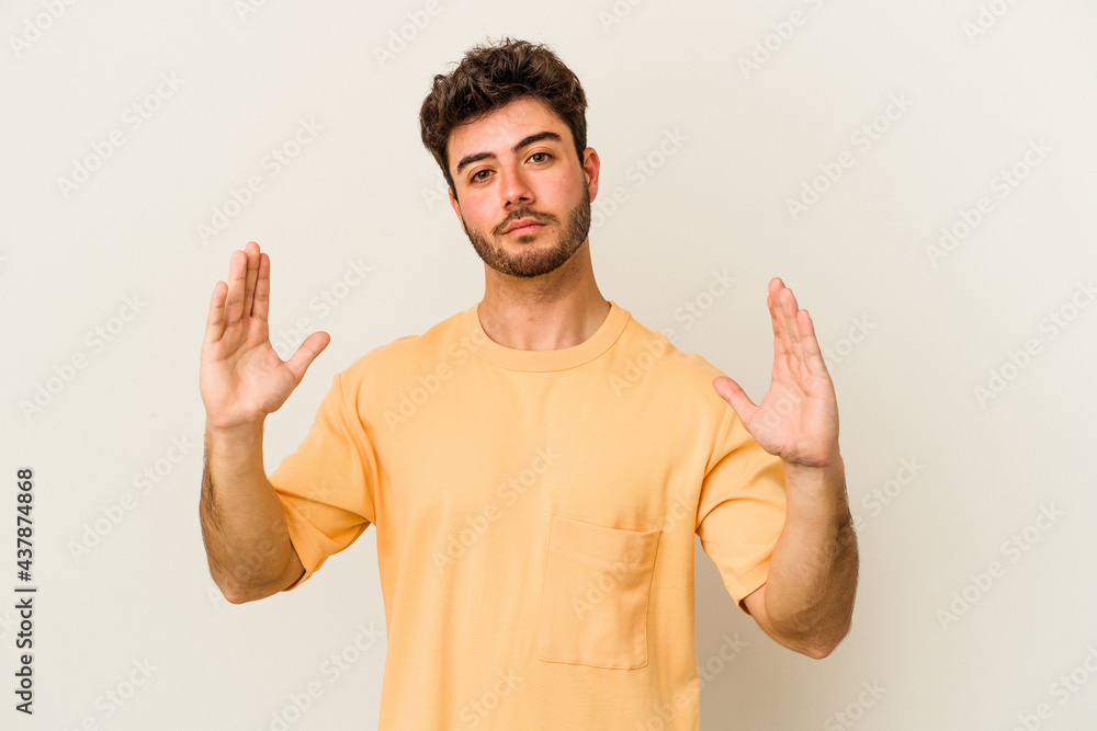 Fototapeta premium Young caucasian man isolated on white background holding something little with forefingers, smiling and confident.