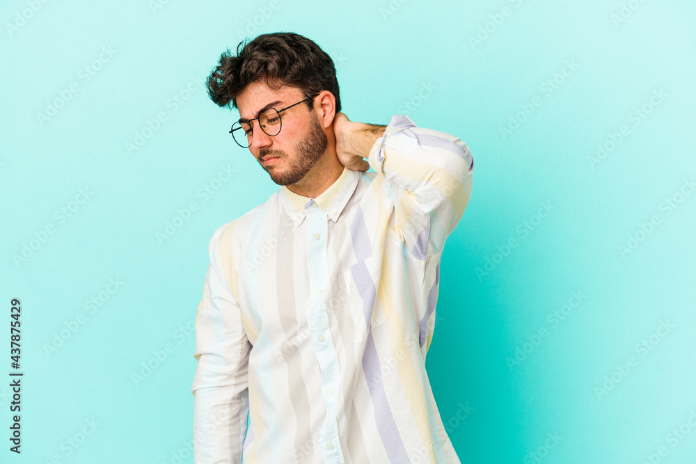 Young caucasian man isolated on blue background having a neck pain due to stress, massaging and touching it with hand. Young caucasian man isolated on blue background having a neck pain due to stress, massaging and touching it with hand.