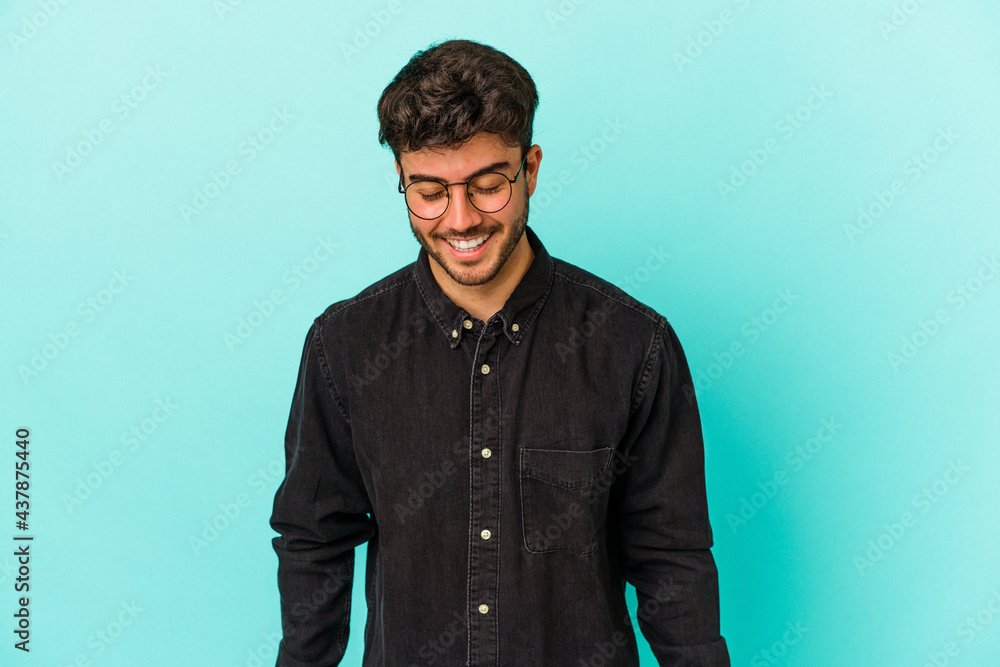 Young caucasian man isolated on blue background laughs and closes eyes, feels relaxed and happy. Young caucasian man isolated on blue background laughs and closes eyes, feels relaxed and happy.