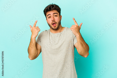 Fotografía Young caucasian man isolated on blue background pointing upside with opened mouth