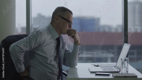 Elderly businessman working with computer in modern office having back ache © nimito