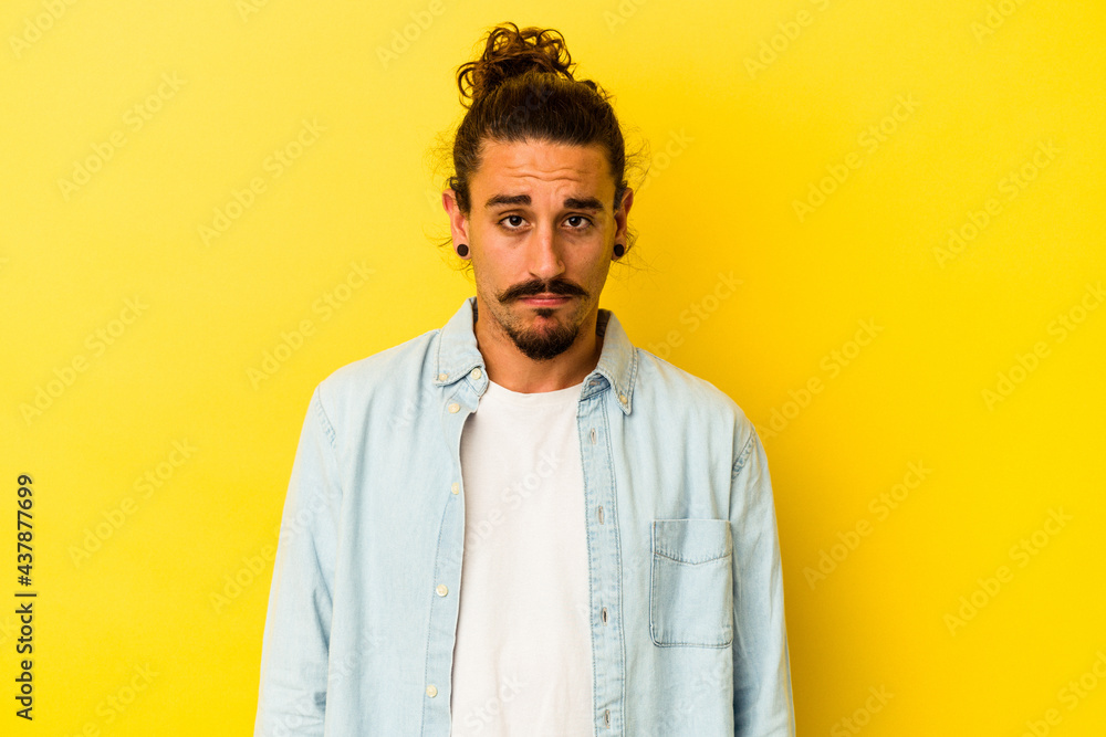 Young caucasian man with long hair isolated on yellow background sad, serious face, feeling miserable and displeased. Young caucasian man with long hair isolated on yellow background sad, serious face, feeling miserable and displeased.