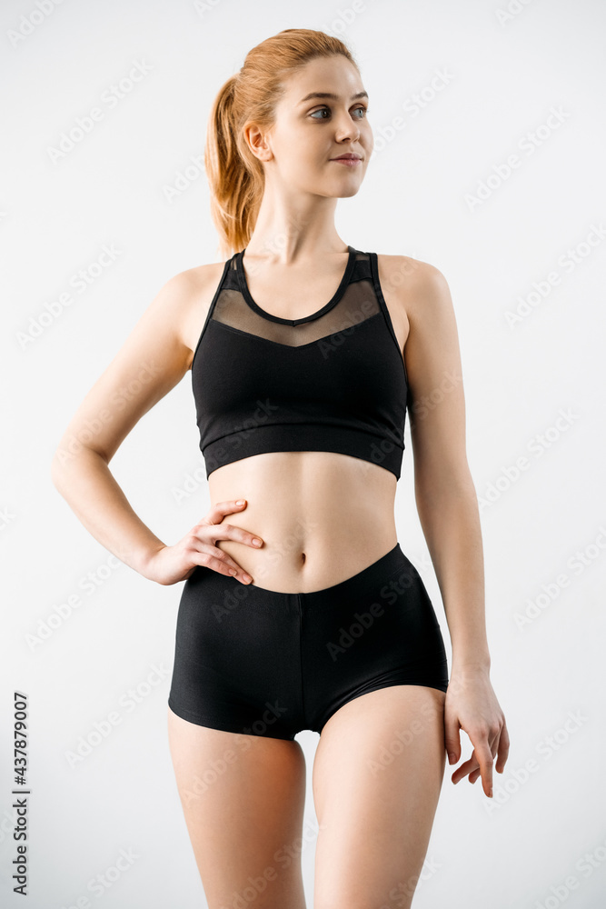 Sportswear fashion. Outfit for training. Activewear design. Fitness clothes. Front view of slim athletic woman in logo mockup black crop top bra shorts isolated on light. Sportswear fashion. Outfit for training. Activewear design. Fitness clothes. Front view of slim athletic woman in logo mockup black crop top bra shorts isolated on light.
