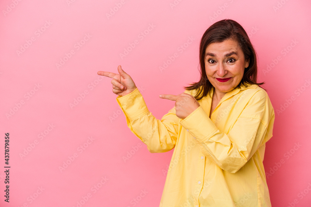 Middle age caucasian woman isolated on pink background pointing with forefingers to a copy space, expressing excitement and desire. Middle age caucasian woman isolated on pink background pointing with forefingers to a copy space, expressing excitement and desire.